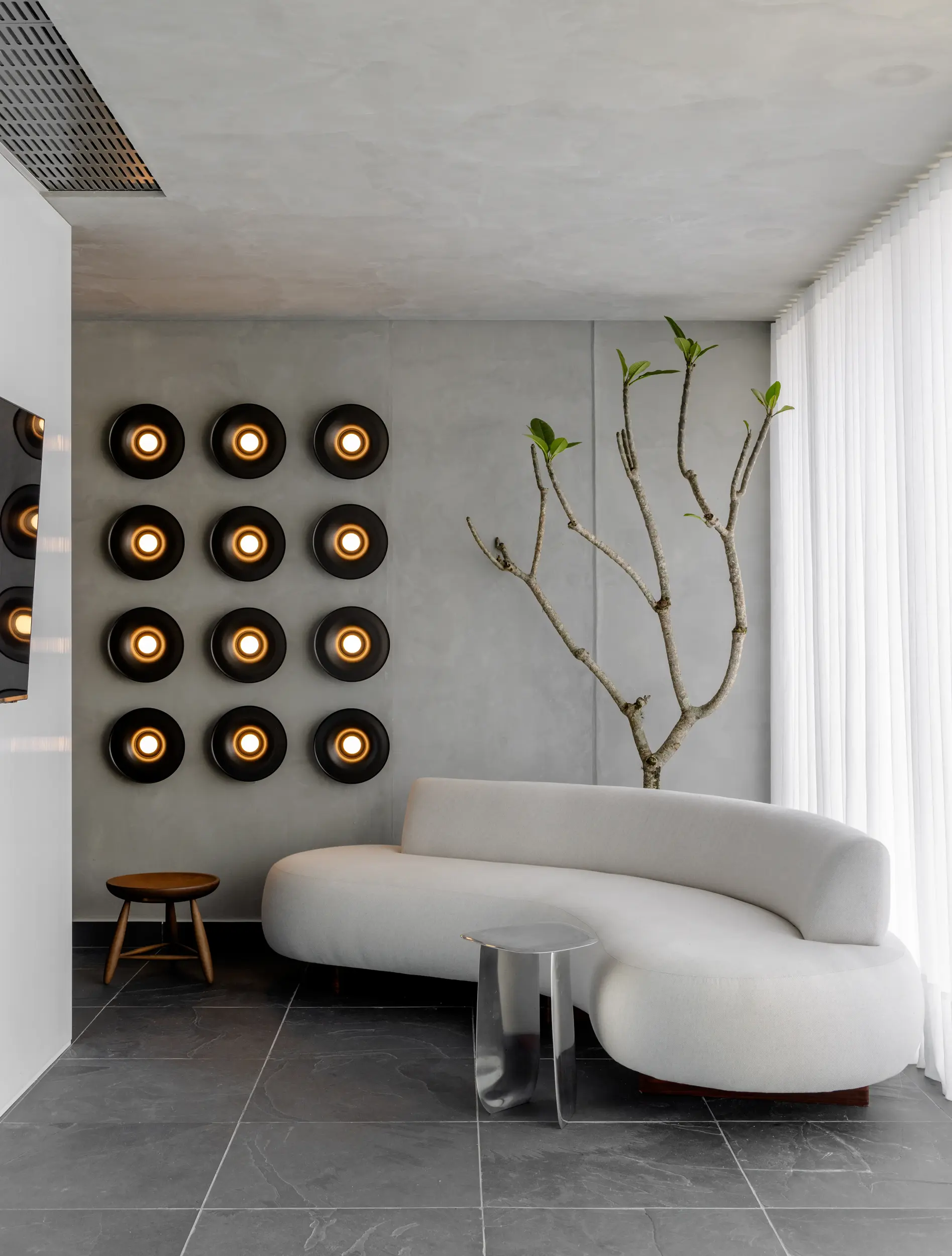 Parede com luminárias circulares e composição artística natural no Apto Prisma, projeto assinado pelo Studio Guilherme Garcia.