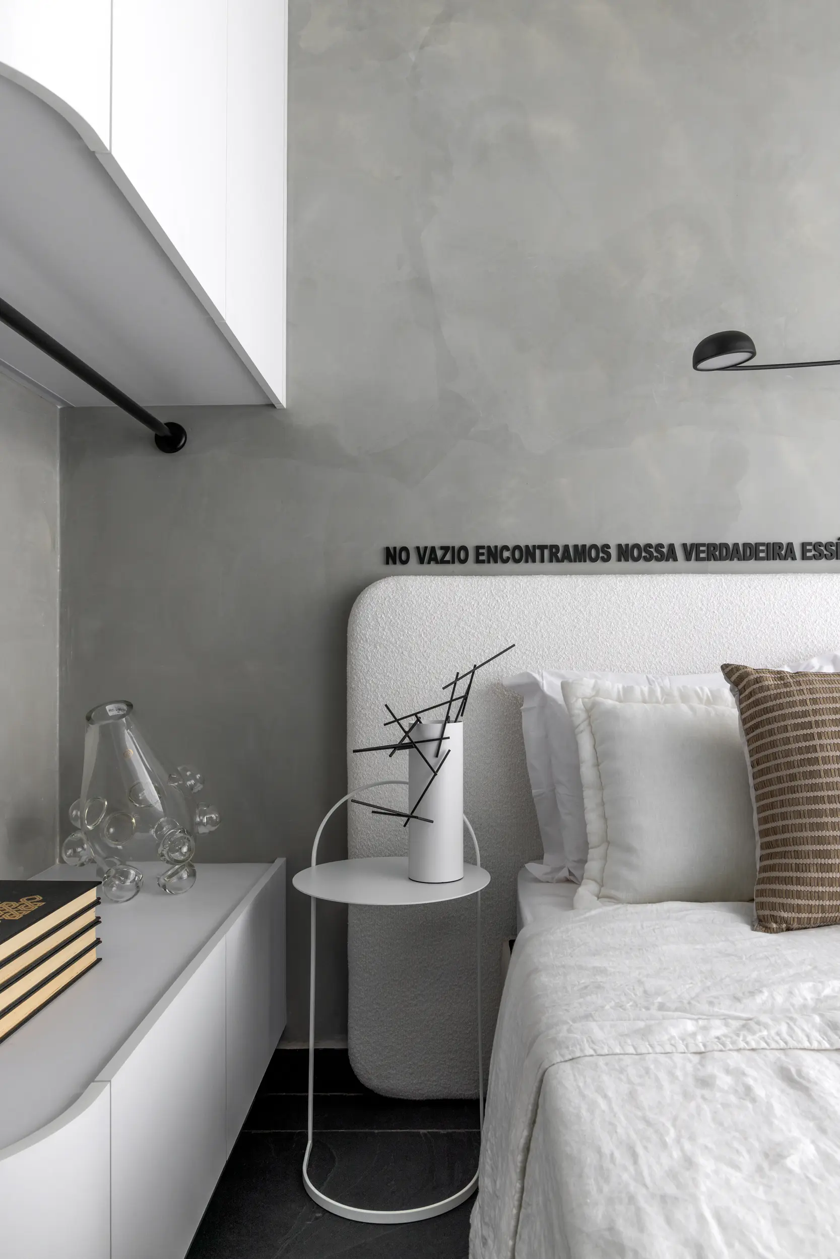 Quarto minimalista com iluminação suave e composição têxtil no Apto Prisma, projeto do Studio Guilherme Garcia.