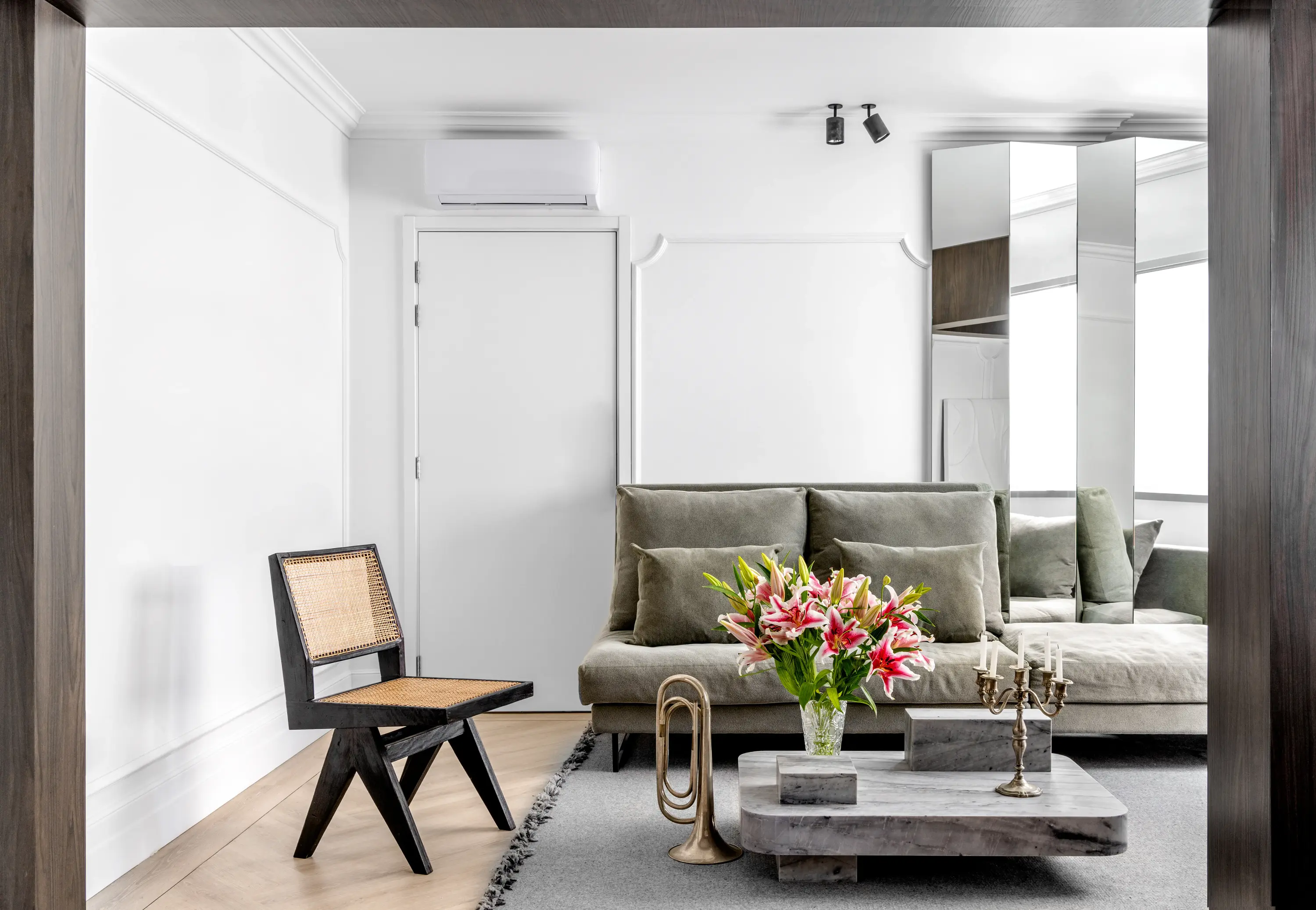 Sala com sofá verde oliva, cadeira de palhinha e arranjo de flores naturais, projeto Lab Paris por Studio Guilherme Garcia.