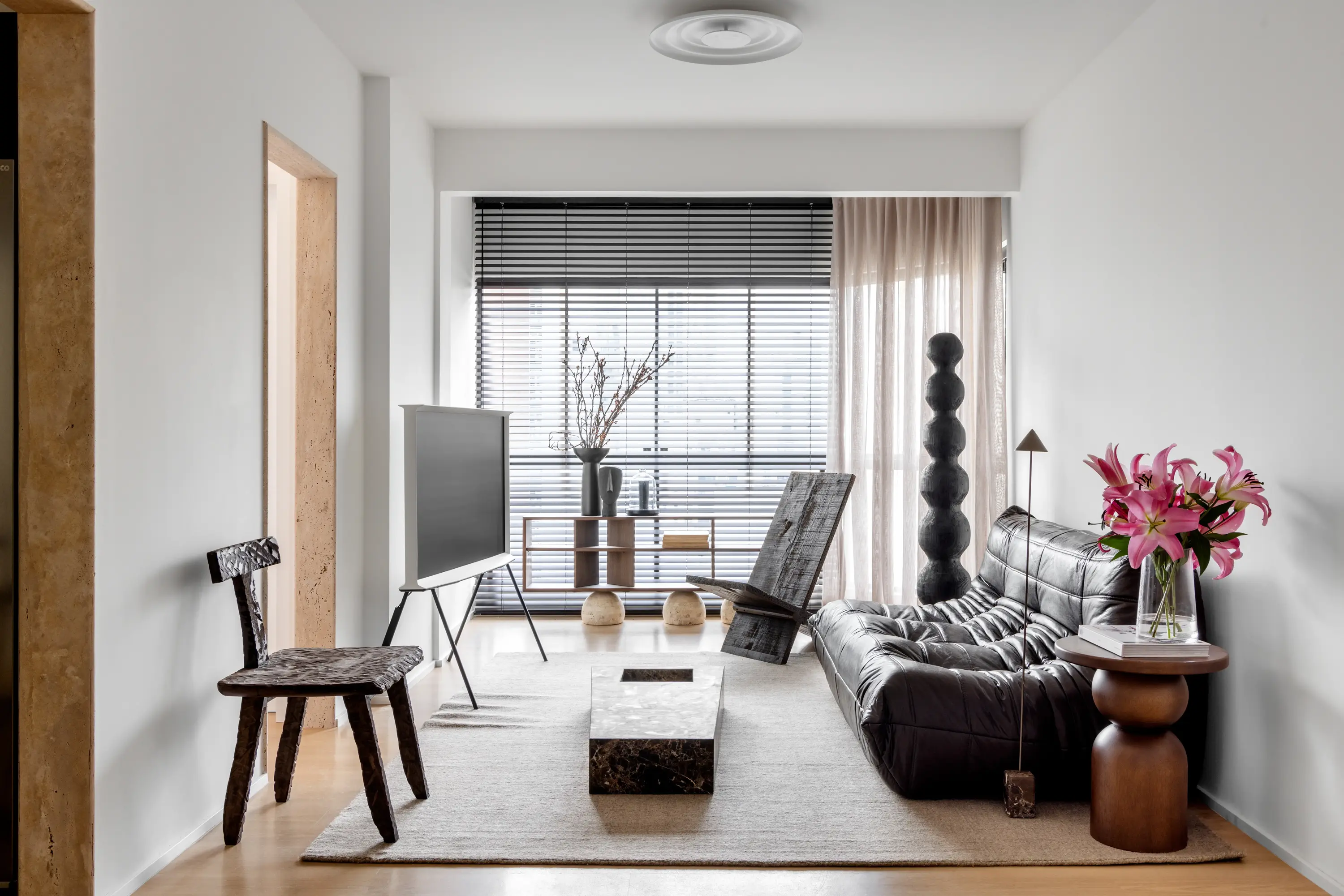 Sala com sofá em couro preto e luminária vertical escultural ao fundo, projeto Lab 06 por Studio Guilherme Garcia.