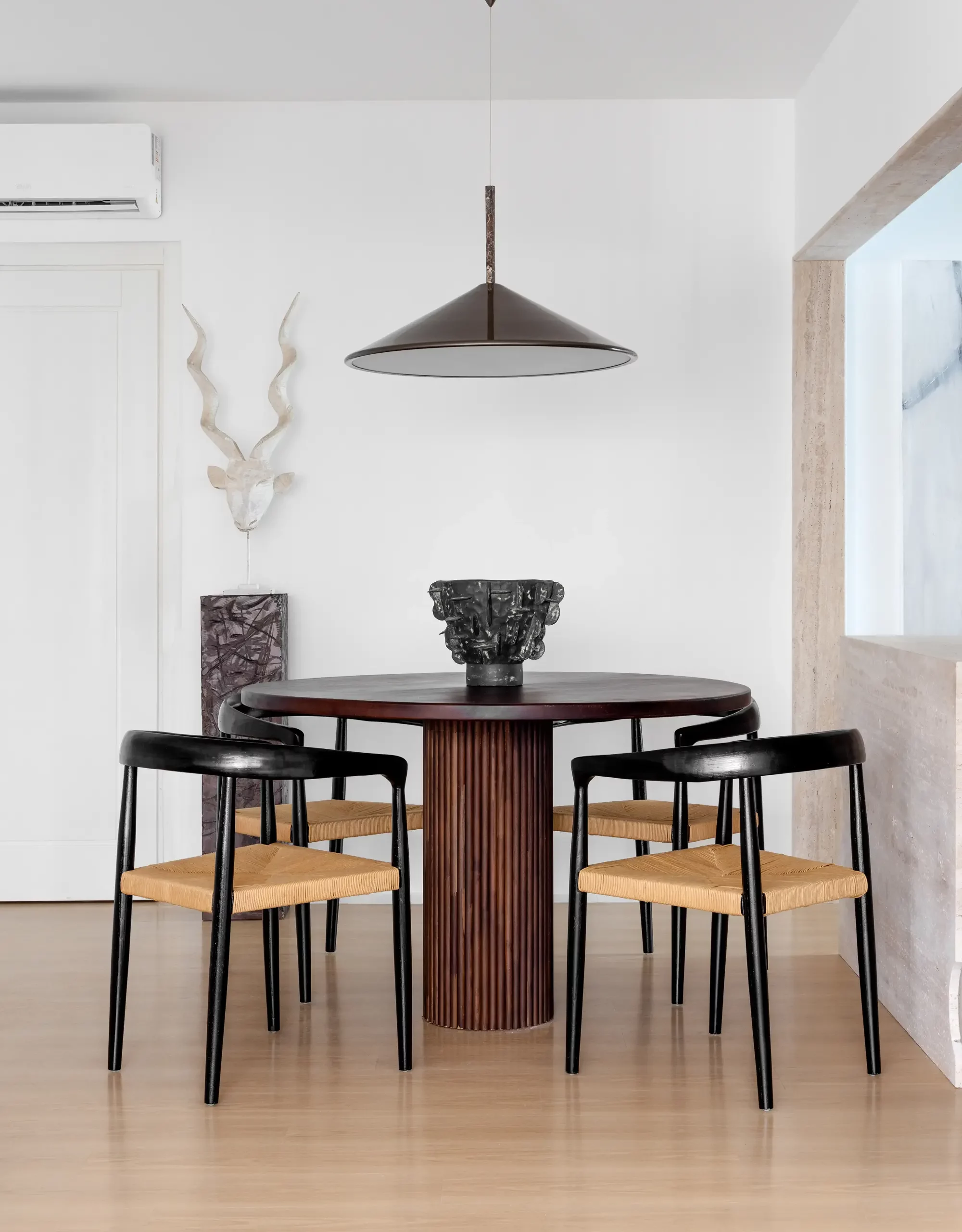 Sala de jantar minimalista com mesa redonda e luminária pendente em preto fosco, projeto Lab 06 por Studio Guilherme Garcia.