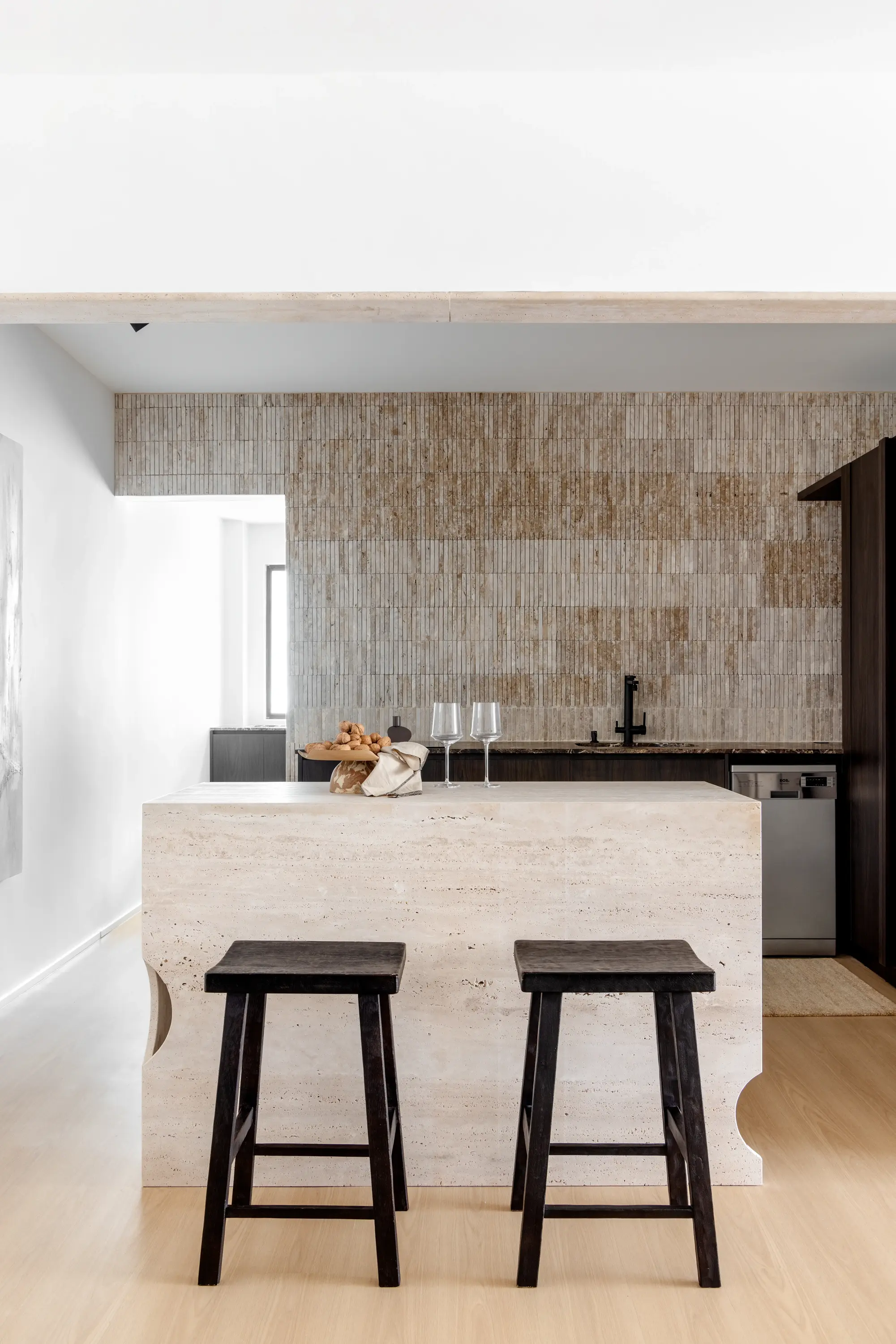 etalhe da ilha em pedra com banquetas pretas e parede em mármore ao fundo, projeto Lab 06 por Studio Guilherme Garcia.