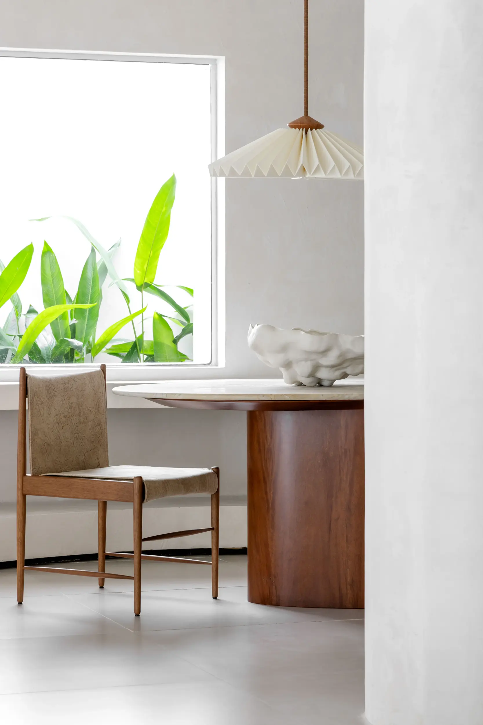 Espaço iluminado com pendente escultural e cadeiras de madeira no projeto Tempo Casa do Studio Guilherme Garcia