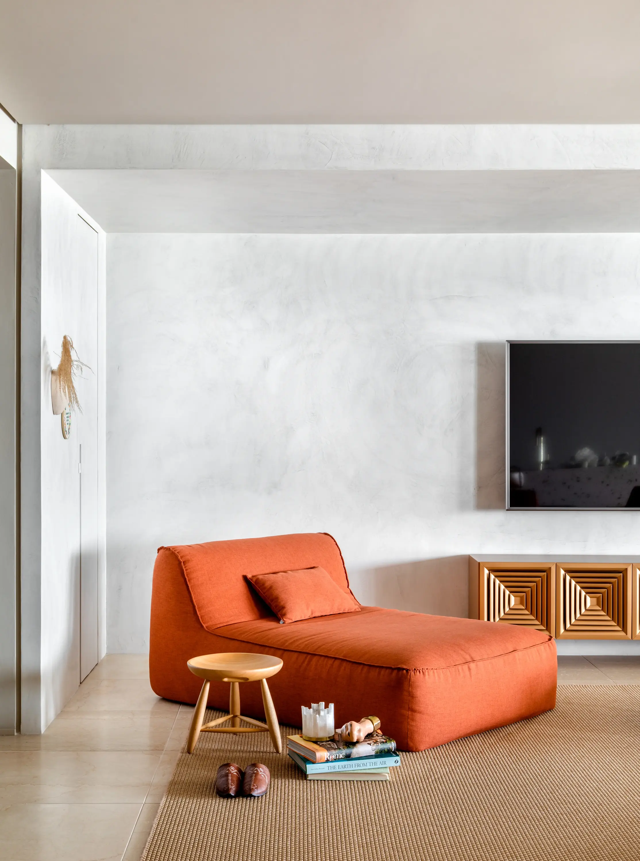 Espaço de leitura com poltrona laranja e estilo moderno no Apto Holidays, design afetivo do Studio Guilherme Garcia.