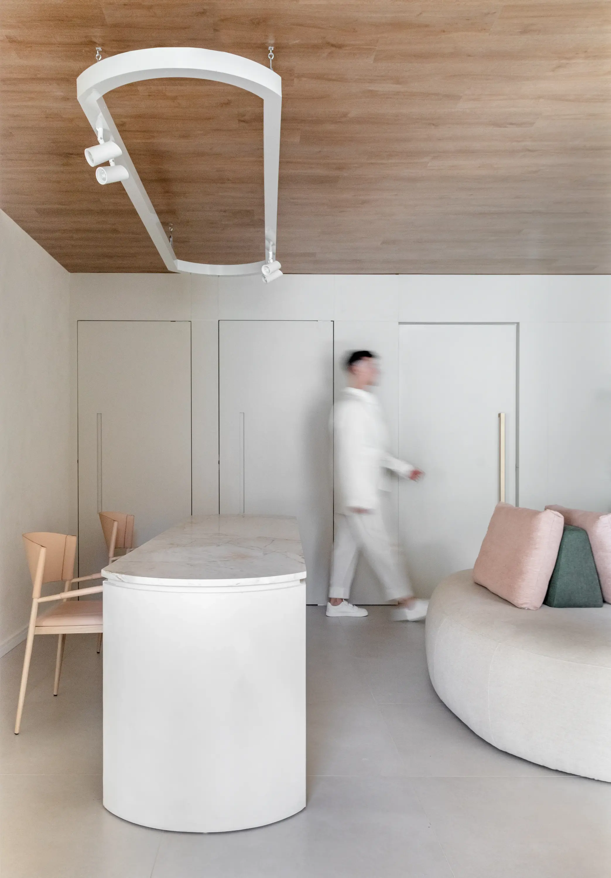 Vista lateral da recepção com circulação fluida e móveis curvos — projeto Clínica Baumgarten por Studio Guilherme Garcia