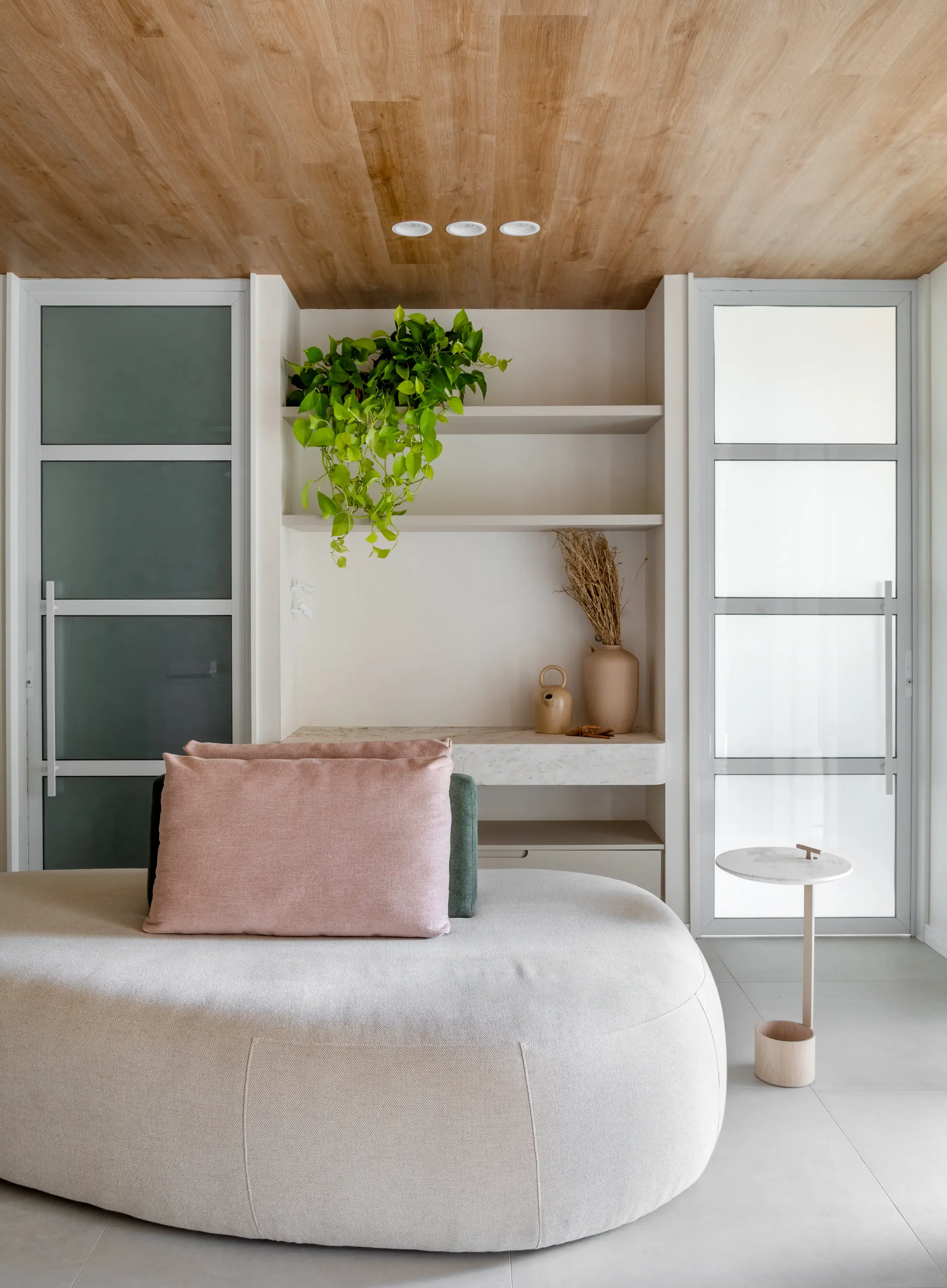 Espaço de espera com sofá curvo e prateleiras iluminadas por iluminação natural — Clínica Baumgarten, Studio Guilherme Garcia