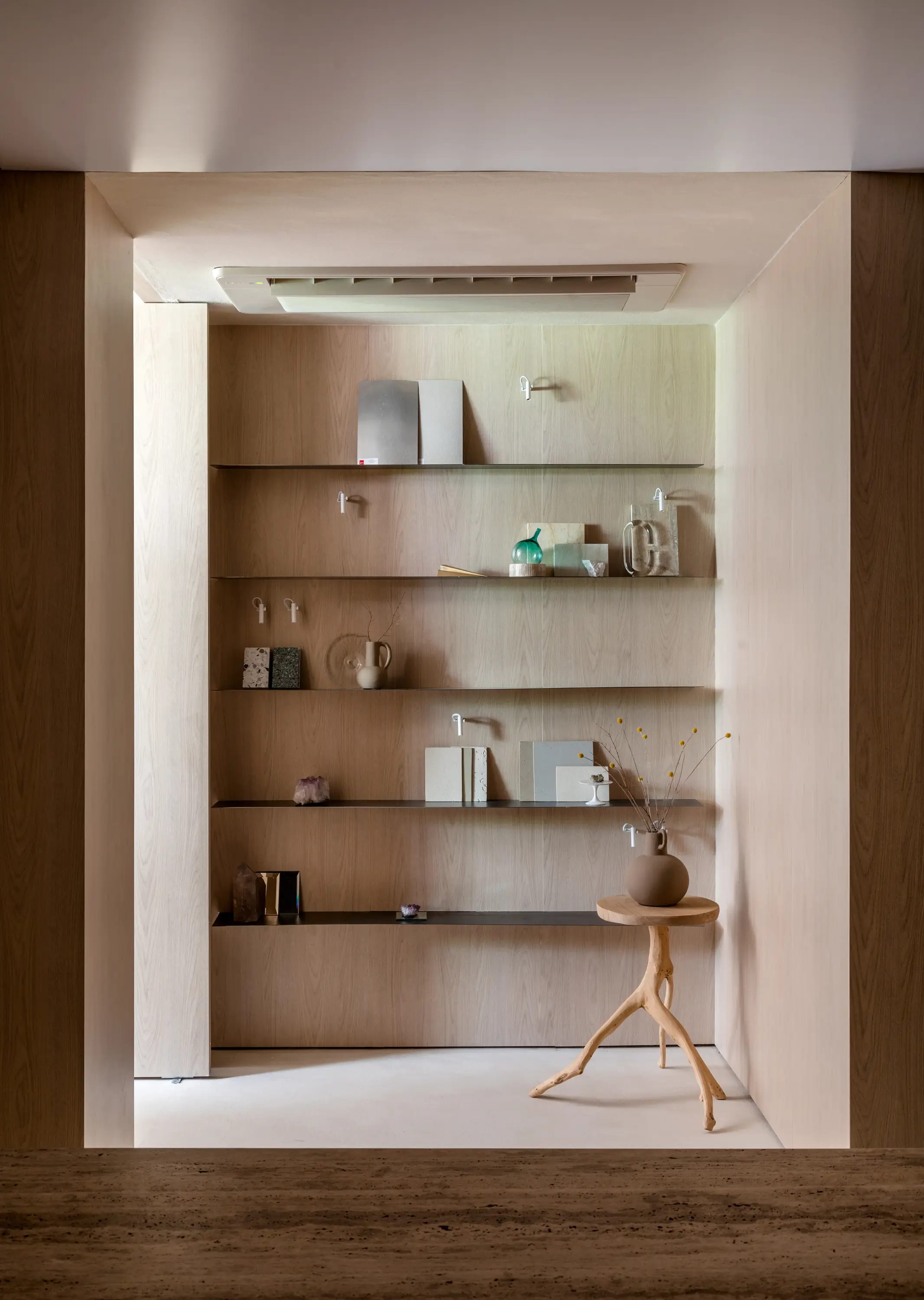 Estante embutida em madeira clara com objetos decorativos e cadeira de design. Escritório WJ por Studio Guilherme Garcia.