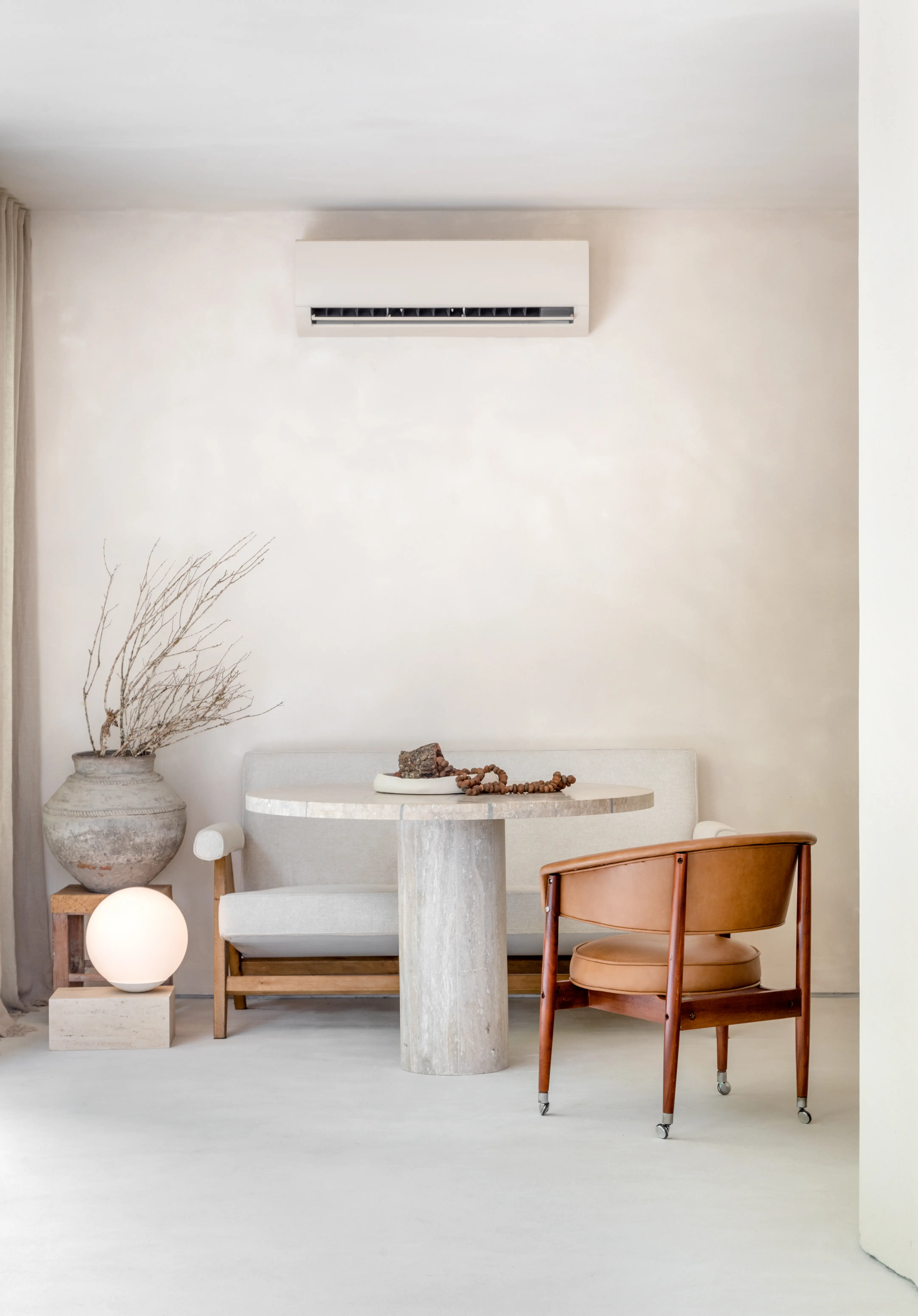 Vista frontal de escritório com banco estofado, mesa em pedra e cadeiras em madeira, projeto Escritório WJ por Studio Guilherme Garcia.