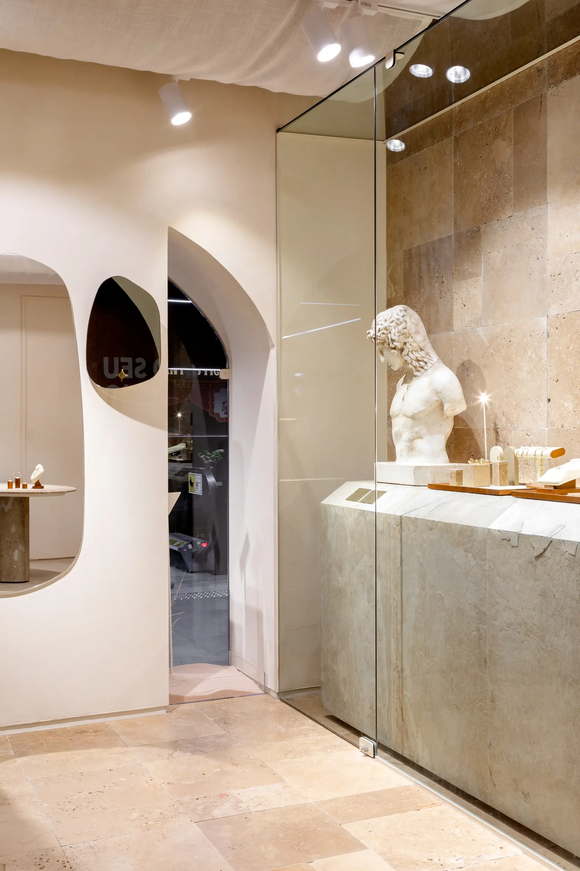 Vitrine com escultura em mármore e iluminação delicada na Moretto Joalheria por Studio Guilherme Garcia