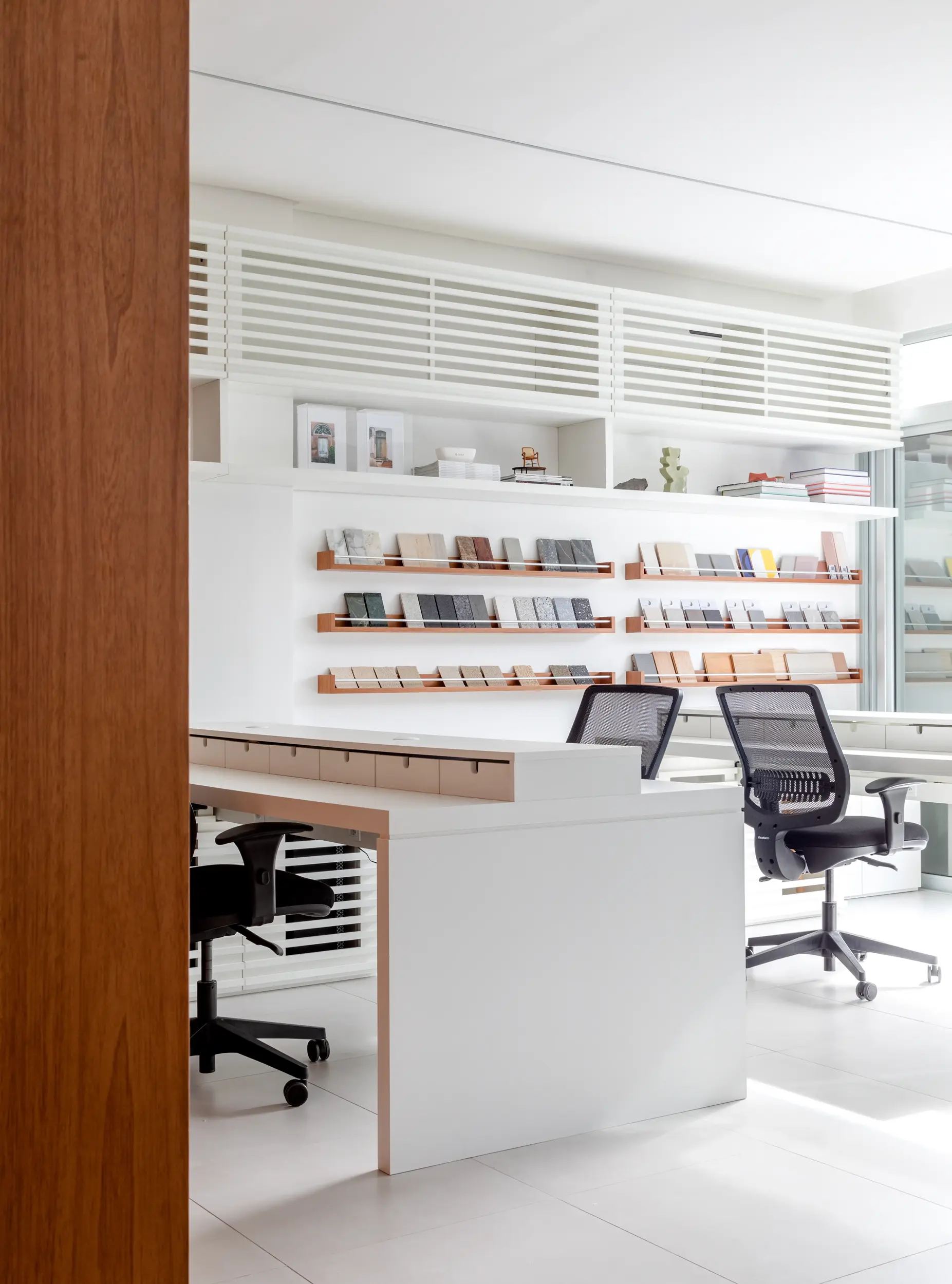 Interior do Escritório SGG com estantes brancas e cadeiras ergonômicas — projeto contemporâneo do Studio Guilherme Garcia